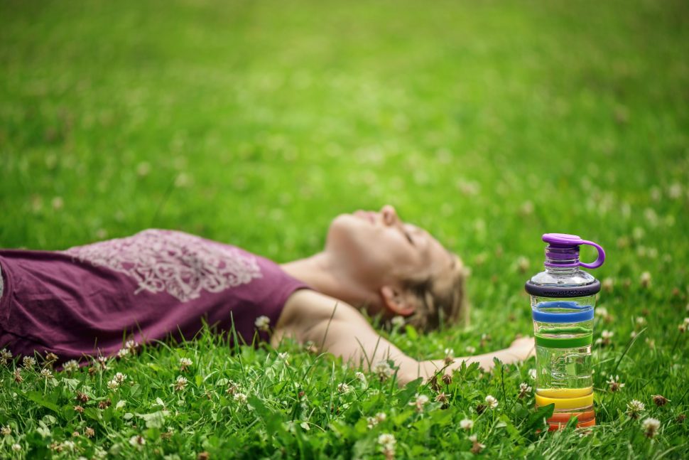 Inteligentná informovaná červená sklenená fľaša na pitie i9 v tráve ležiaca žena